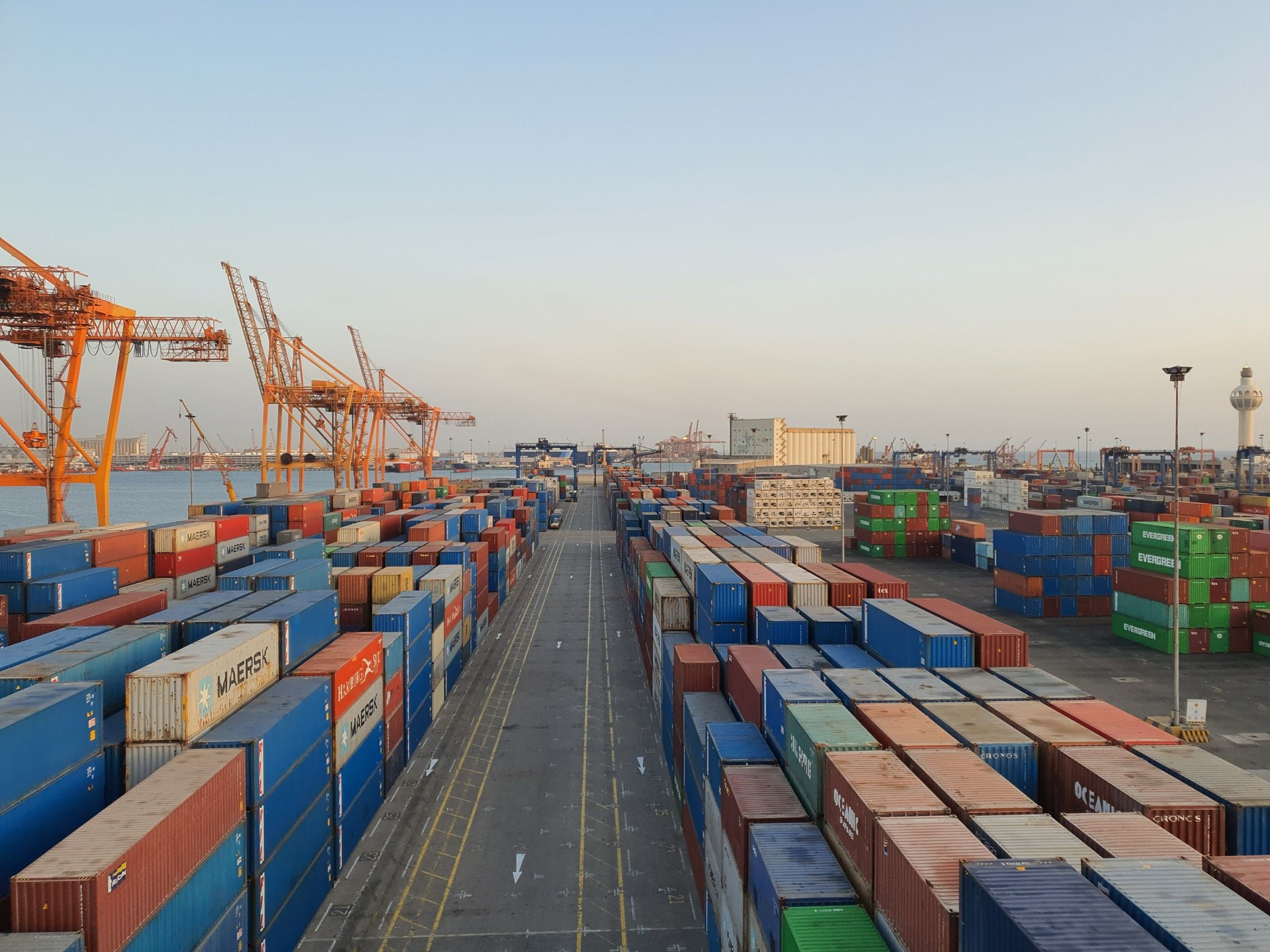 Rows of colorful shipping containers at a sunlit port terminal